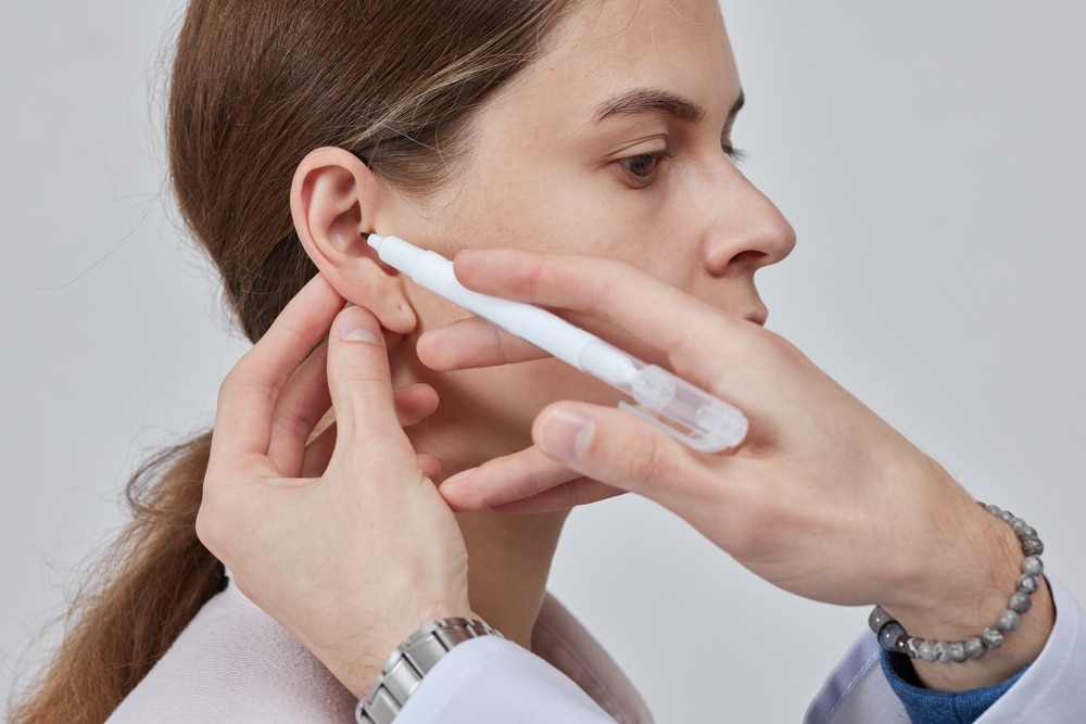 Doctor marking patient’s ear during evaluation for reconstructive surgery to treat microtia or ear deformities.