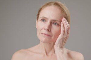 Woman touching face, representing recovery and considerations after facial reconstructive surgery in a clinical context