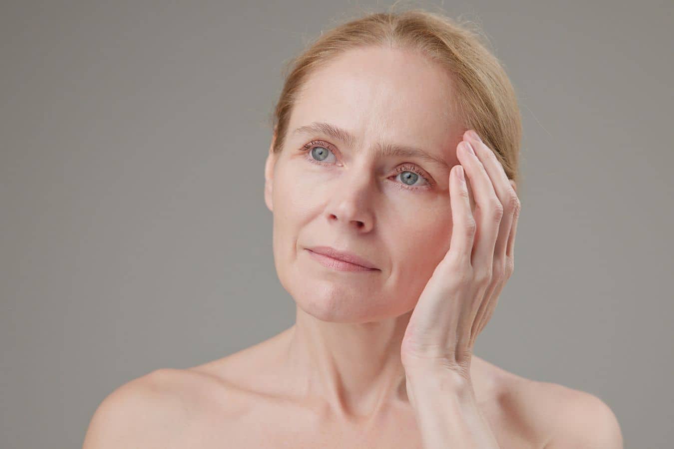 Woman touching face, representing recovery and considerations after facial reconstructive surgery in a clinical context