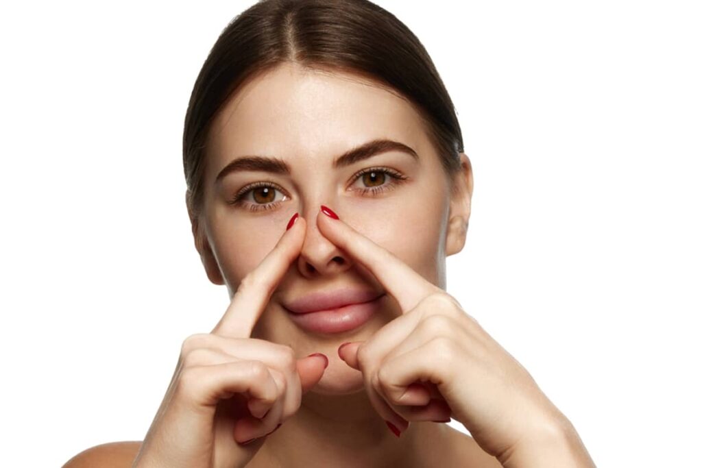 Woman gently touching the sides of her nose during rhinoplasty recovery.